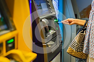 Woman hand insert a credit card into an ATM machine.