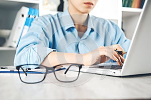 Woman hand keyboard with glasses on desk