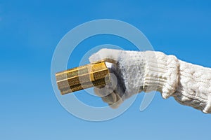 Woman hand in the knitted gloves with small gold gift boxe. Winter concept. photo