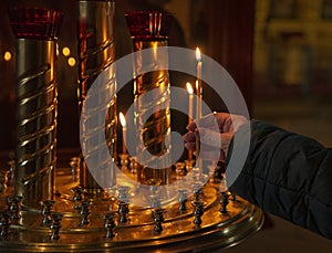 Woman hand lighting candles in a church