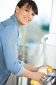 woman hand loading dirty clothes in washing machine