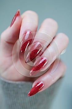 Woman hand with long nails and a bottle of brown red nail polish