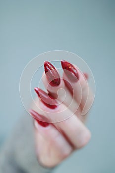Woman hand with long nails and a bottle of brown red nail polish