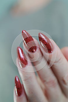 Woman hand with long nails and a bottle of brown red nail polish