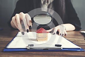 Woman hand magnifier and house model
