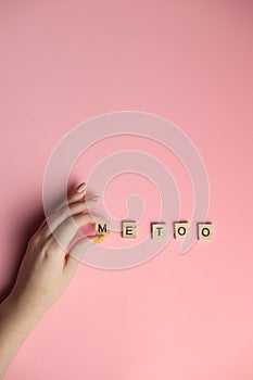 Woman hand making MeToo word with wooden alphabet on pink background, used for concept of sexual harrassment