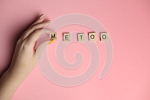 Woman hand making MeToo word with wooden alphabet on pink background, used for concept of sexual harrassment