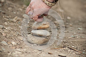 Woman hand making stone balance in the sand