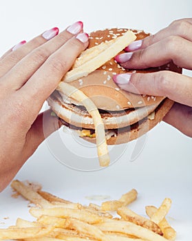 Woman hand with manicure holding big burger french fries on background, people eating food concept