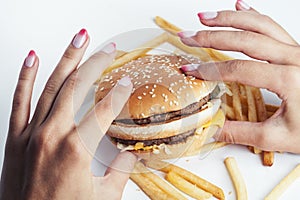 Woman hand with manicure holding big burger french fries on background, people eating food concept