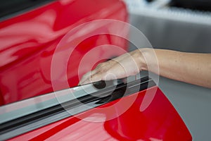 Woman hand on open the new red car door background