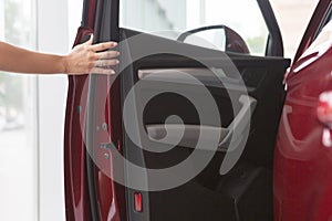 Woman hand on open the new red car door background