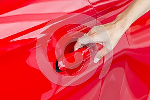 Woman hand on open the new red car door background