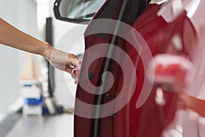 Woman hand on open the new red car door background