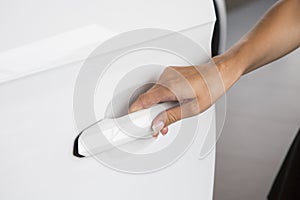 Woman hand on open the new white car door background