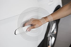 Woman hand on open the new white car door background