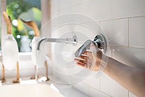 Woman hand open water tap to fill bathtub