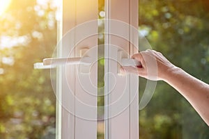 woman hand open white plastic window at home. The concept of ventilation