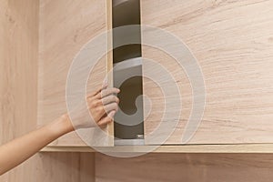 Woman hand open wooden cupboard doors