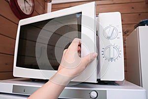 Woman hand opening microwave oven in order to prepare, heat food for lunch or dinner, kitchen elecrtric appliances using