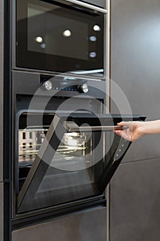 Woman hand opening new modern built-in oven on kitchen