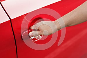 Woman hand opening red car door, close-up