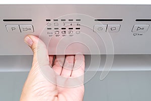 Woman hand opening washing machine in the middle if a washing cycle in order to check proper work of the kitchen