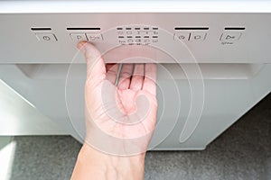 Woman hand opening washing machine in the middle if a washing cycle in order to check proper work of the kitchen