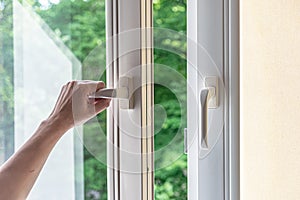 Woman hand opens a plastic window for airing. Modern plastic windows