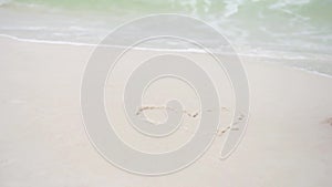 Woman hand paint heart symbol on beach sand. Ocean Waves in background. Pensacola Beach, Florida