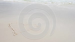 Woman Hand Paint Heart Symbol on beach Sand. Pensacola Beach, Florida.