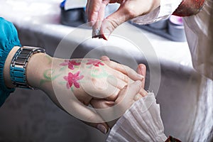 Woman hand painting a red flowers on a kids hand