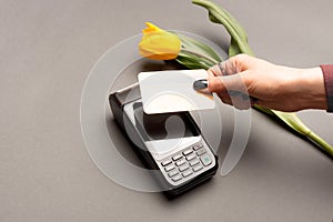 woman hand paying with credit card by paypass near yellow tulip