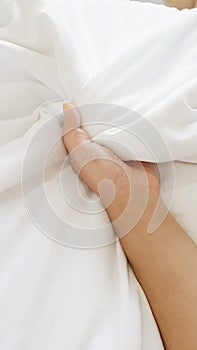 Woman hand peck the white blanket on the bed photo