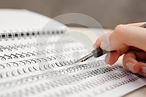 Woman hand with pen for calligraphy writing in a notebook