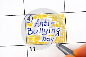 Woman hand with pen writing reminder Anty - Bullying Day in calendar