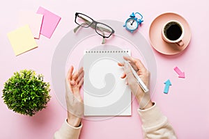 Woman hand with pencil writing on notebook and hold coffee cup. Woman working on office table with coffee