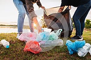 woman hand picking up garbage plastic bag for cleaning at park