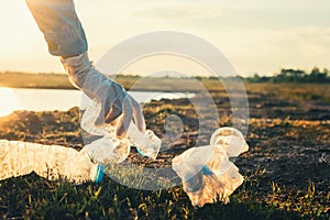 woman hand picking up garbage plastic bottle for cleaning at park