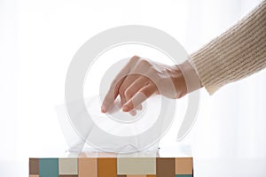 Woman hand picking white tissue paper from tissue box. Healthcare concept