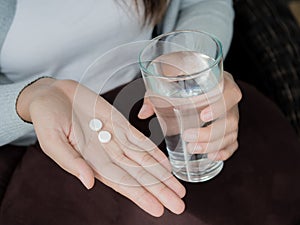 Woman hand with pills medicine tablets and glass of water