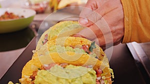 Woman hand placing fresh homemade tacos on a plate
