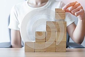 Woman hand placing wood block on the building. Leadership, Business process planning, Risk Management and strategy Concepts