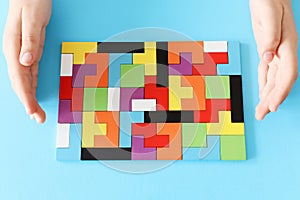 Woman hand placinga tangram puzzle, over wooden table