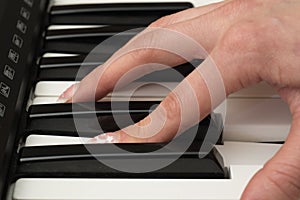 Woman hand playing a MIDI controller keyboard synthesizer close up