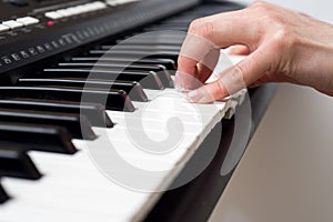 Woman hand playing a MIDI controller keyboard synthesizer close up