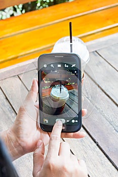 Woman hand playing smartphone and coffee on wooden table