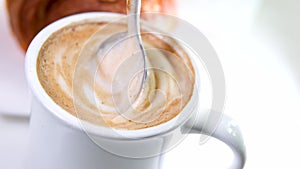 Woman hand pouring sugar and stirring coffee with spoon, coffee time. Stirring latte coffee with a spoon. High quality