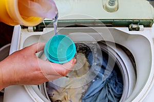 Woman hand pouring washing powder into the washing machine photo