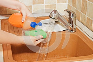 Woman hand pours a washing-up liquid photo